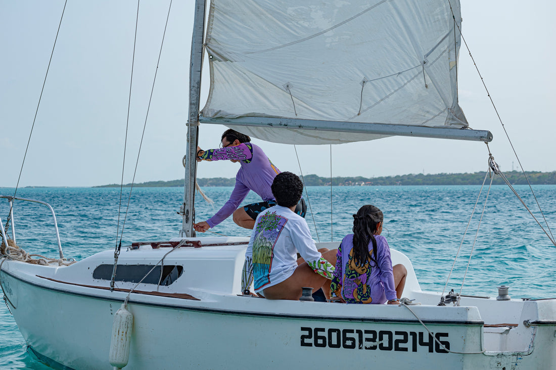 A group of people sailing on a boat wearing long sleeved sun protective shirts.